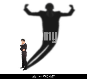 Business-Mann stehen und wirft Schatten eines starken Mannes Stockfoto