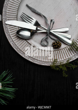 Vintage oder rustikale Weihnachten Tabelle mit eleganten weißen Teller, Besteck und natürlichen Pine Tree Branch auf Holz- Oberfläche Stockfoto