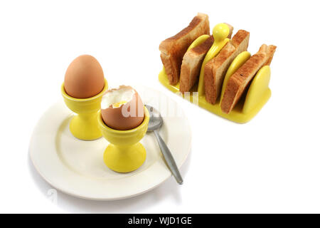 Zwei weich gekochte Eier mit Toast im Sonnenschein gelb Eierbecher und passenden Toast Rack Stockfoto