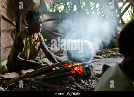 ONNI DORF, Neuguinea, Indonesien - Juni 24: Die Frau von einem Stamm von Papua korowai kocht das Essen. Korowai Kombai (Kolufo). Am 24. Juni 2012 in Onni Vil Stockfoto