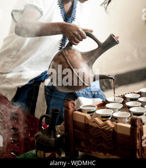 Woman's Hand Kaffee Gießen für die traditionellen äthiopischen Kaffee Zeremonie Stockfoto