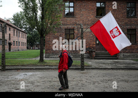 Polen, OSWIECIM-14 August 2019: Der Mann mit der polnischen Flagge, Weiß und Rot, während die Katholiken gegenüber Vernichtungslager Auschwitz-Birkenau zu Fuß Stockfoto