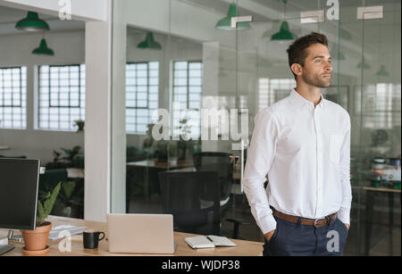 Junge Unternehmer tief in Gedanken beim Stehen in einem Büro Stockfoto