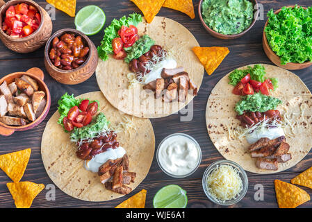 Tacos mit Füllungen auf dem hölzernen Tisch Stockfoto