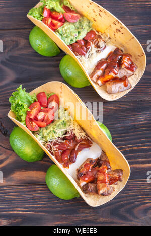 Tacos mit Füllungen auf dem hölzernen Tisch Stockfoto