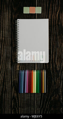 Leeres Papier mit farbigen Linien, Bunte Bleistifte und Radiergummis auf dem Holztisch. Ansicht von oben Stockfoto