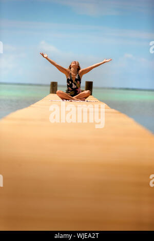 Gerne Mitte der erwachsenen Frau wirft die Arme, während er auf dem Pier. Stockfoto