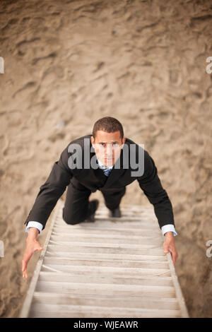 Geschäftsmann, klettern die Leiter am Strand Stockfoto