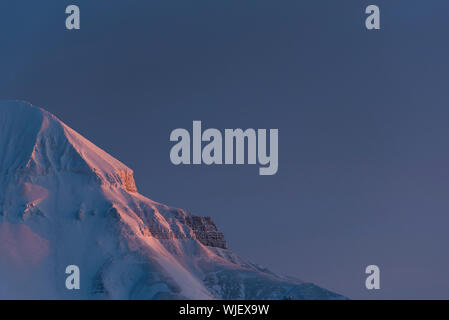 Sonnenuntergang auf der Seite der schneebedeckten Berge auf Spitzbergen Stockfoto