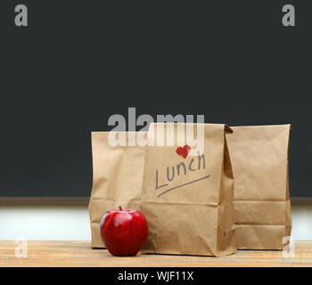 Mittagessen Papiertüten mit roter Apfel auf Schulbank Stockfoto