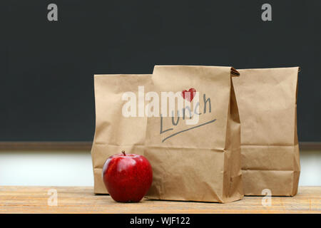 Mittagessen Papiertüten mit roter Apfel auf Schulbank Stockfoto