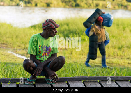 Neuguinea, Indonesien - Juni 26: Der lokale Papua Mann beobachtet wie die Porter transfers Gepäck. Am 26. Juni 2012 in unbekannten Dorf, Neuguinea, Ind Stockfoto