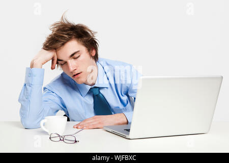 Jungen Mann im Büro mit dem Laptop auf seine front und schlafen erschöpft Stockfoto
