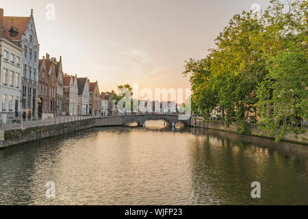 Schönen Kanal mit bunten stein zweistöckige Häuser, Bäume und eine Brücke aus Stein, in der Dämmerung, in Brügge, Belgien. Stockfoto