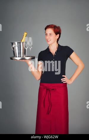 glückliche junge Kellnerin Champagner auf einem Tablett serviert Stockfoto