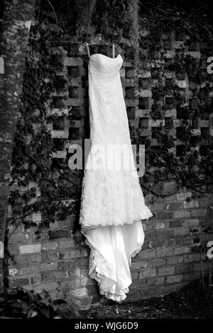 White Wedding Dress hängen von Efeu bedeckt Wand Stockfoto
