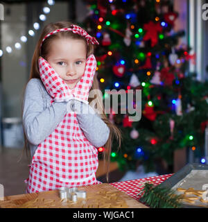 Entzückendes kleine Mädchen trug Handschuhe Lebkuchen Weihnachtsplätzchen Backen Stockfoto