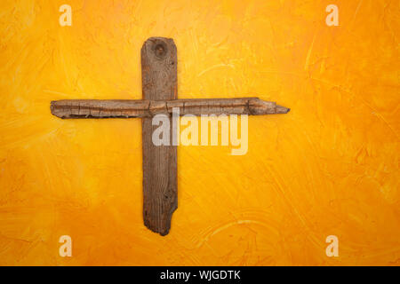 Rugged Holzkreuz an gelbe Wand hängen Stockfoto