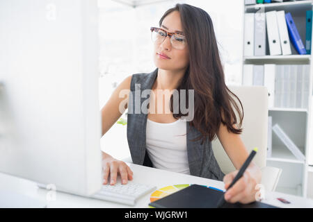 Lässig weiblich Photo Editor mit Grafiktablett in einem hellen Büro konzentriert Stockfoto