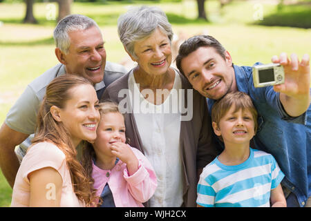 Glückliche großfamilie selbst fotografieren mit Digitalkamera im Park Stockfoto