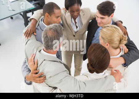 Diverse Business Team umarmen in einem Kreis im Büro Stockfoto