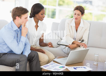 Business Team Meetings über die Zahlen auf der Couch im Büro zu gehen Stockfoto