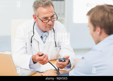 Arzt seine Patienten Blutdruck in seinem Büro im Krankenhaus Stockfoto