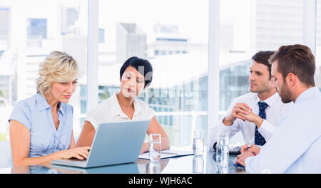 Intelligent junge Führungskräfte sitzen um besprechungstisch im Büro angezogen Stockfoto