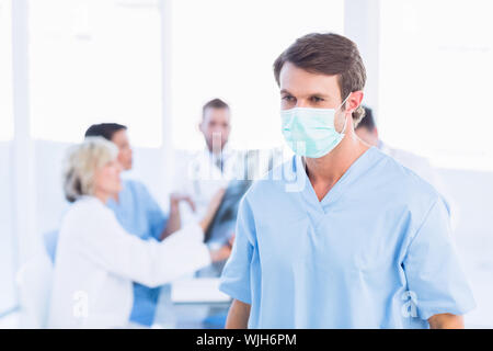Männliche Chirurg das Tragen einer Maske mit Kollegen in der Sitzung an einem medizinischen Büro Stockfoto