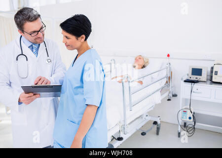 Ärzte diskutieren Berichte mit Patienten im Hintergrund am Krankenhaus Stockfoto