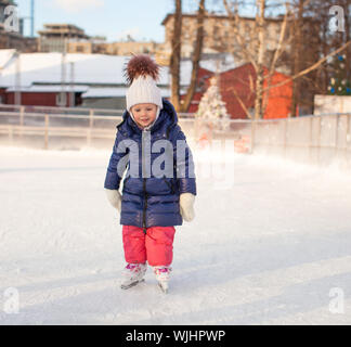 Entzückende kleine Mädchen in der Skate auf weißem Eis Stockfoto