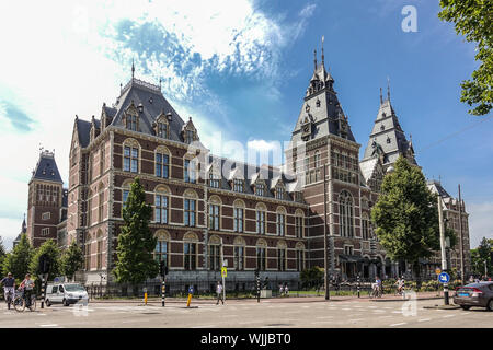 Amsterdam, Niederlande - 30. Juni 2019: Weite Einstellung der Rijksmuseum monumentale Fassade mit Türmen in beige und roten Ziegeln. Unter blau-whtie cloudscap Stockfoto