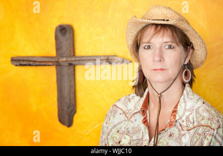 Westliche Frau mit robusten hölzernen Kreuz hängen gelbe Wand Stockfoto