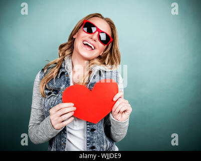 Closeup Portrait der fröhliche junge weibliche Beteiligung an Händen roten herzförmigen romantische Grußkarte, Valentinstag, Teenager Liebe Konzept Stockfoto