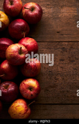 Deep Red Royal Gala Äpfel auf einem rustikalen Holztisch mit sanfter Beleuchtung Stockfoto