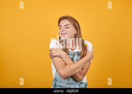 Junge Frau tragen weiße t-shirt, über orange Hintergrund zeigt Emotionen Stockfoto