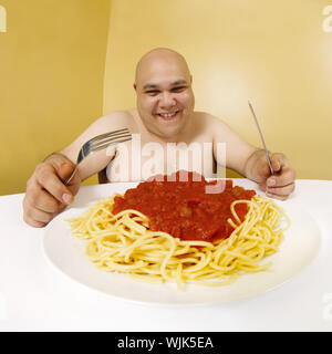 Ein übergewichtiger Mann mit einem Teller Spaghetti. Shot mit Fish-eye Objektiv. Schwerpunkt liegt auf dem Gesicht. Stockfoto