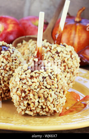 Äpfel mit Karamell mit frischen Äpfeln und Kürbissen im Hintergrund. Stockfoto