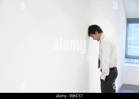 Seitenansicht einer unglücklichen Geschäftsmann ruhender Kopf gegen Wand Büro Stockfoto