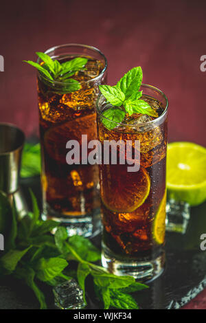 Kalte Longdrink Cuba Libre mit brauner Rum und frische Kalk in highball Glas mit Wassertropfen auf dunklem Hintergrund, selektiver Fokus Stockfoto