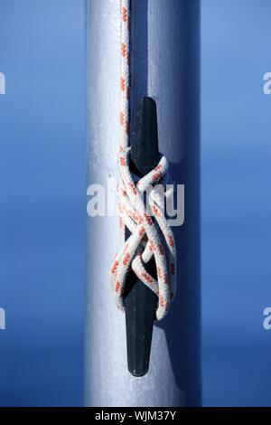 Marine Seil, Knoten nahe einem Stahlmast, blaue Wasser Hintergrund Stockfoto