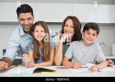 Portrait von lächelnden Paar Kind Hilfe bei den Hausaufgaben in der Küche zu Hause. Stockfoto