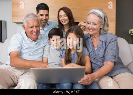 Glückliche Großfamilie mit Laptop auf dem Sofa im Wohnzimmer zu Hause Stockfoto
