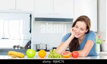 Lächelnde junge Frau mit Früchten auf Zähler in der Küche zu Hause. Stockfoto