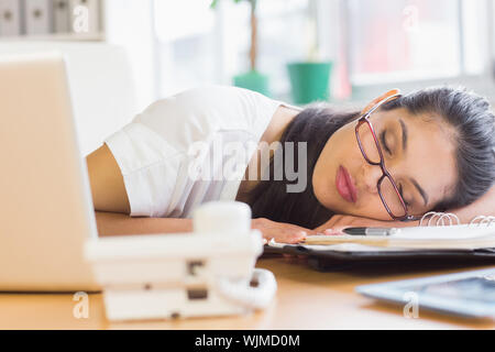 Überarbeitete Geschäftsfrau schlafen auf dem Schreibtisch im Büro Stockfoto