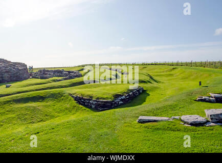 Broch von Gurness durch Erde Banken flankiert von Stein verstärkt. Die broch Dorf Ruinen umgeben es. Stockfoto