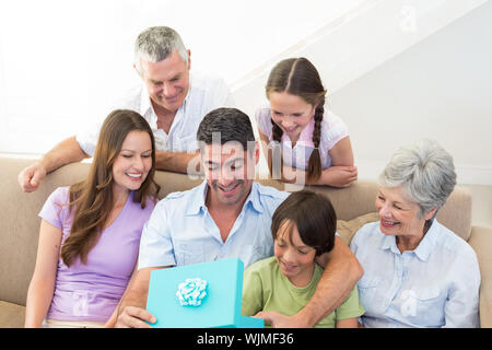 Multigeneration Familie sucht bei man öffnen Geburtstagsgeschenk zu Hause Stockfoto