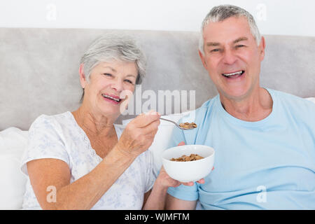 Portrait von gerne ältere Frau Fütterung Getreide in Haus Mann Stockfoto