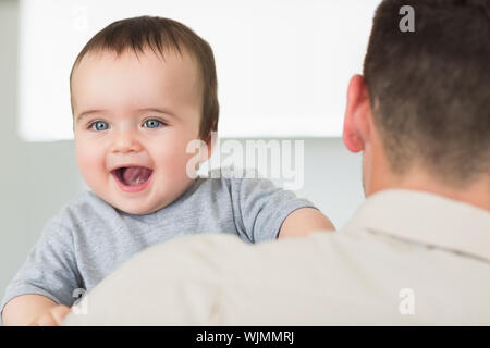 Fröhliches baby boy von Vater zu Hause durchgeführt Stockfoto