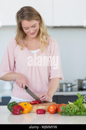 Junge Frau schneiden Gemüse auf Schneidebrett in der Küche Stockfoto